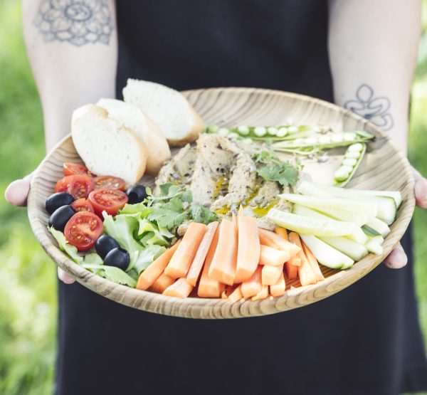 přírodní talíř z teakového dřeva velký s obložených chlebem a zeleninou v dlaních